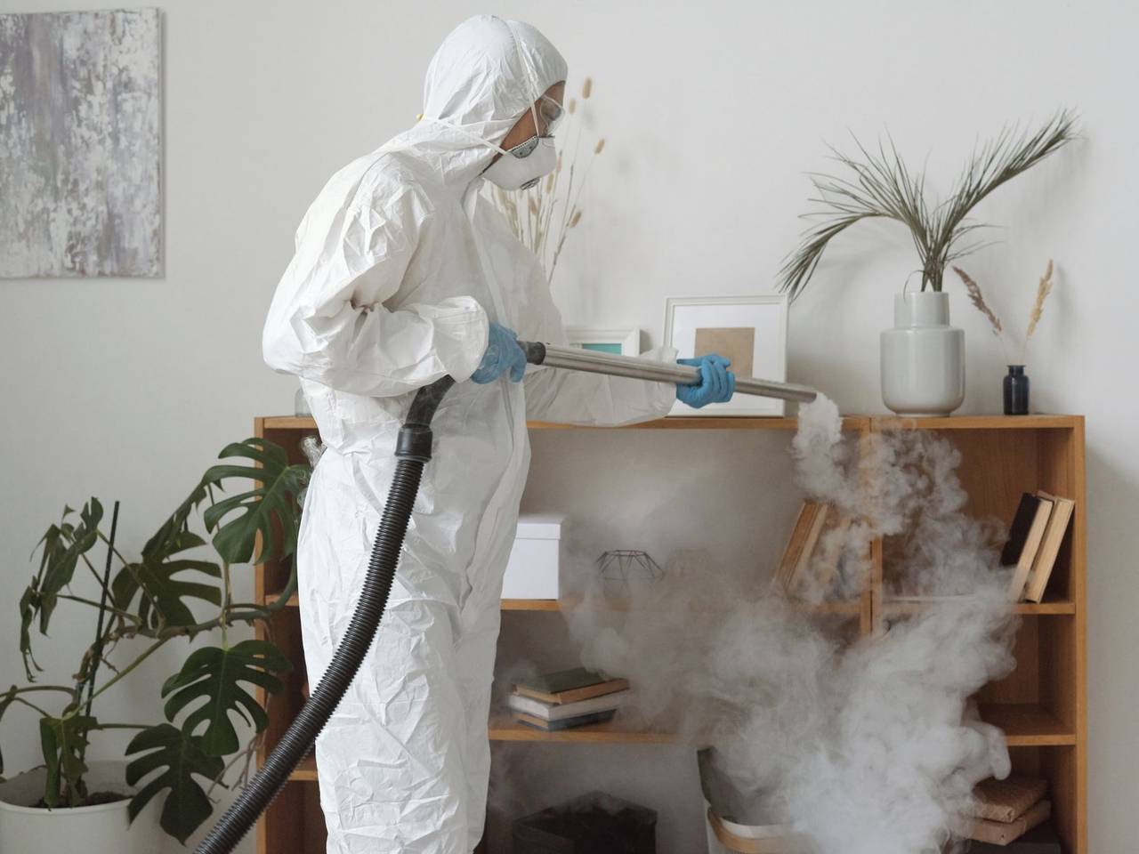Técnico con traje de protección aplicando tratamiento con nebulizador en una sala de estar